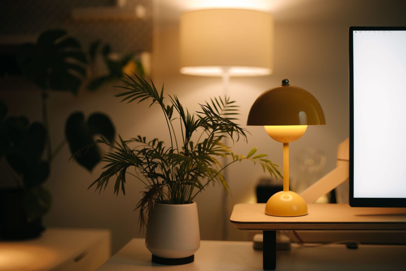 A warm home office desk with a lamp, notebook and plant