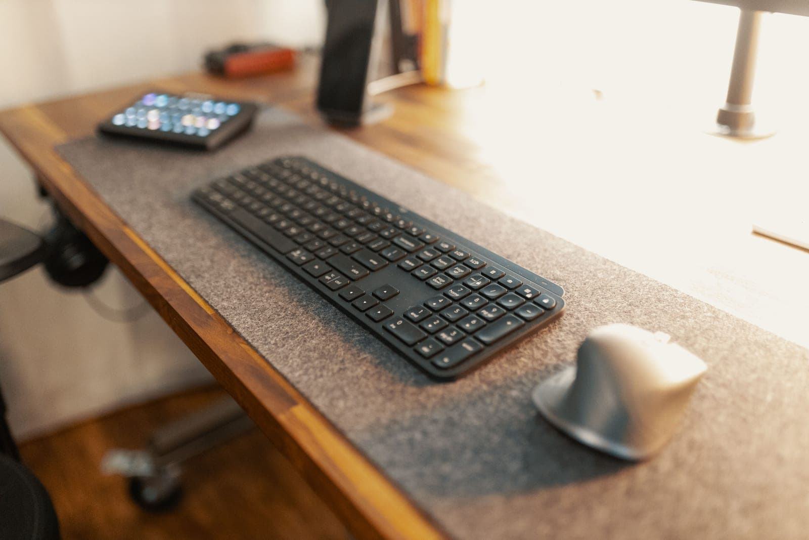 A gray felt desk mat under a laptop in a warm office