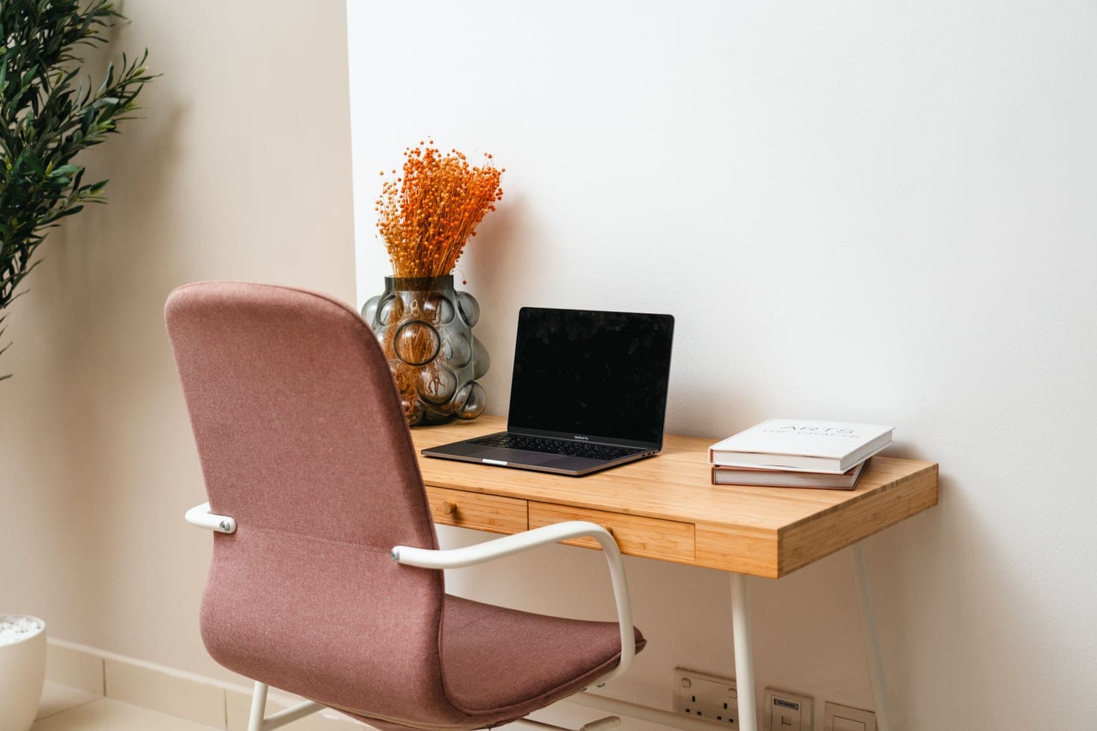 A small compact desk in the corner of a room with a laptop