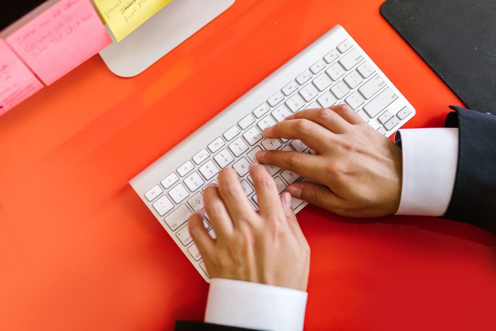 Hands typing on a keyboard at a desk