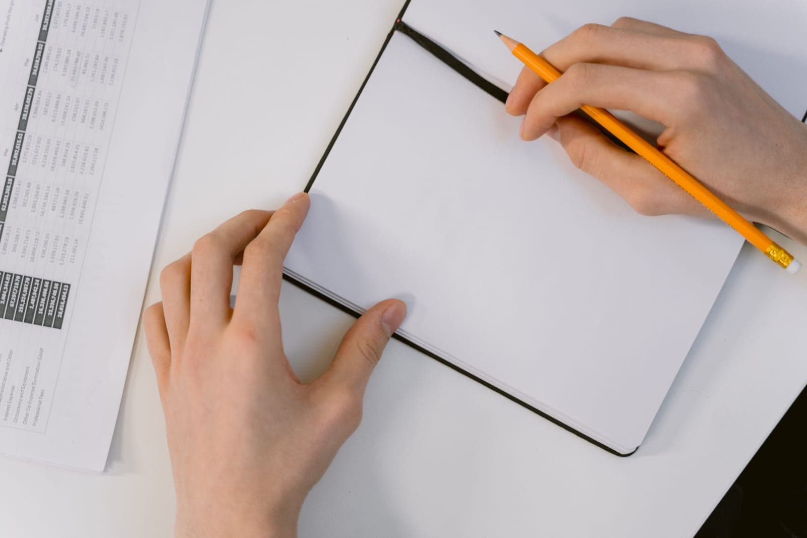 A person holding a blank planner open at a desk, deciding