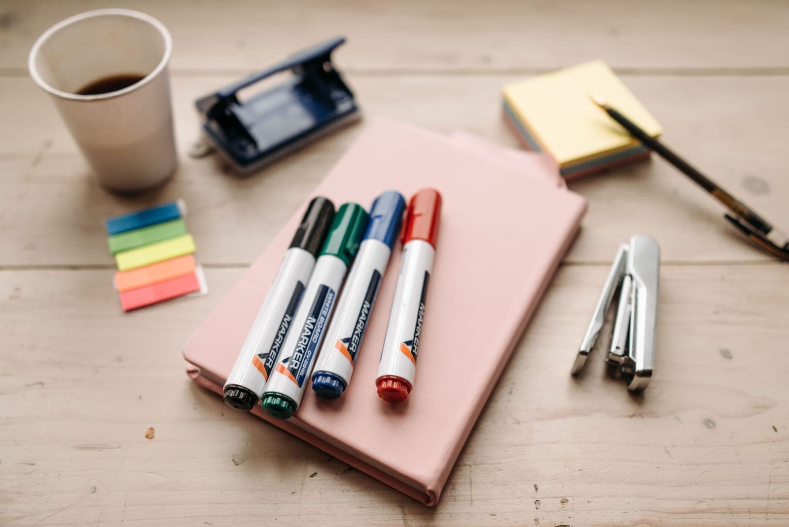 Notebooks, pens and pencils arranged on a warm wooden desk