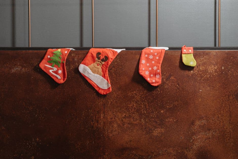 Four Christmas stockings hanging in a row against a warm rust-colored wall