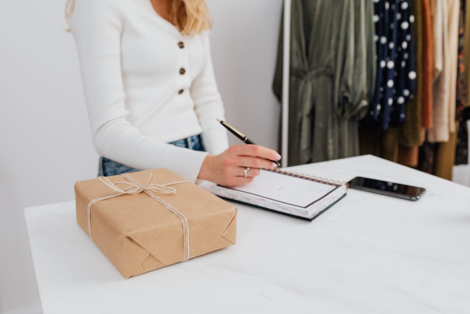 A wrapped gift box beside a notebook and pen on a wooden table