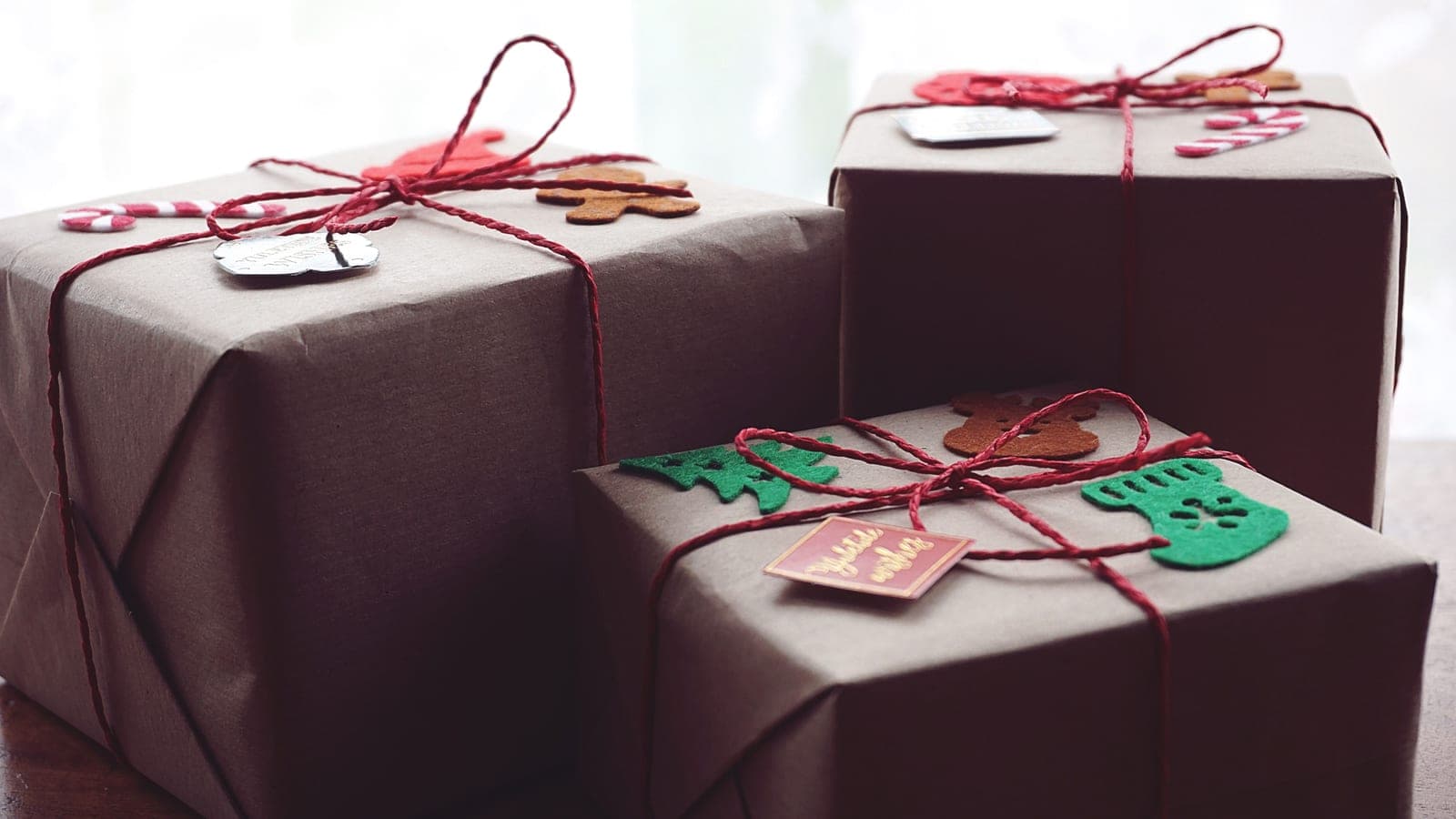 Gifts wrapped in brown paper and twine on a warm wooden table