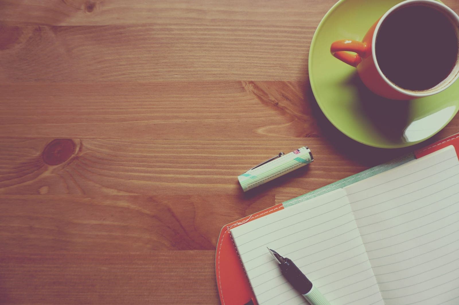An open paper planner and a fountain pen on a wooden desk in warm daylight