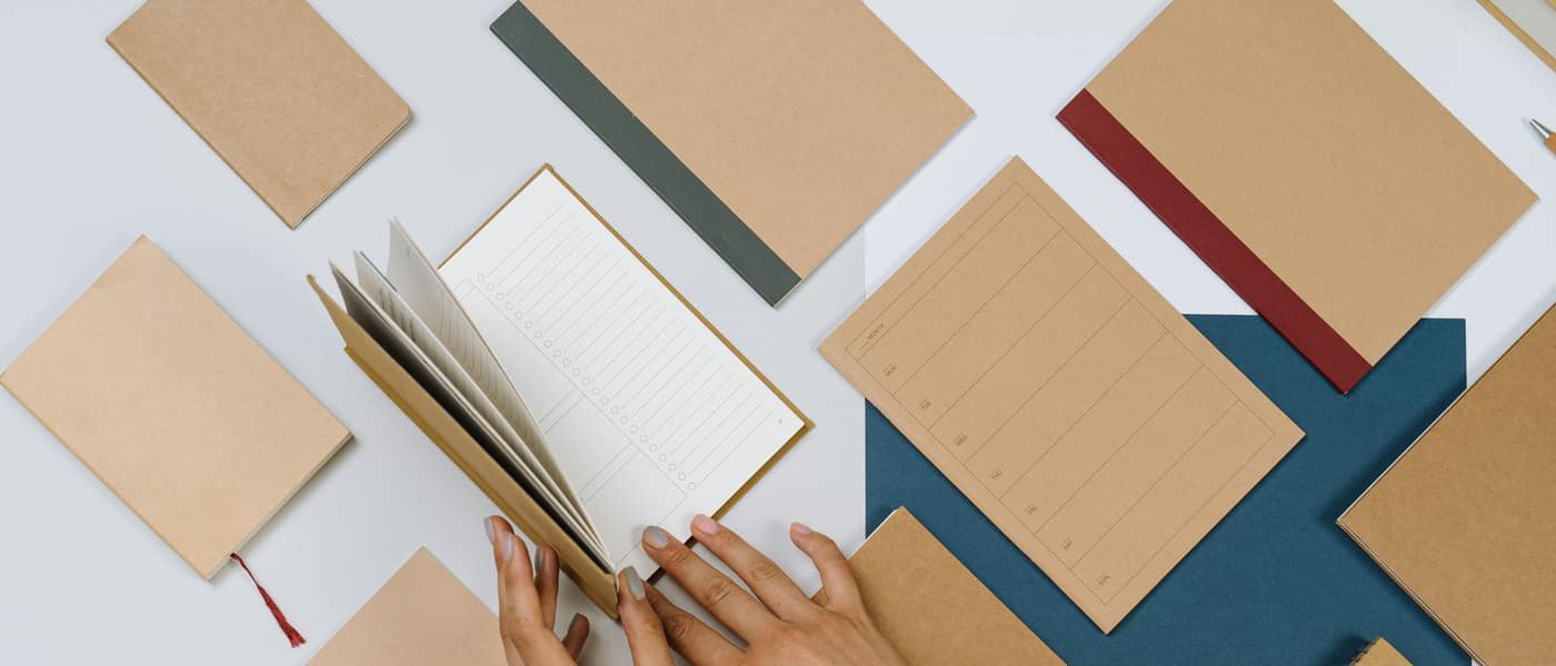 Kraft-covered pocket notebooks arranged on a pale surface, one open