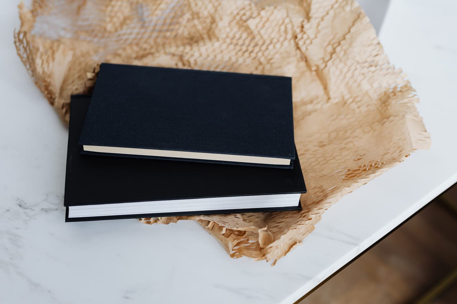 Two black hardcover notebooks side by side on a desk