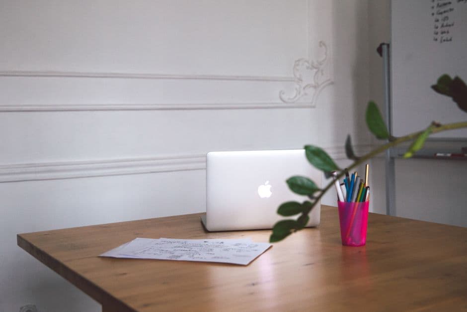 A tidy desk with a laptop, handwritten notes and pens