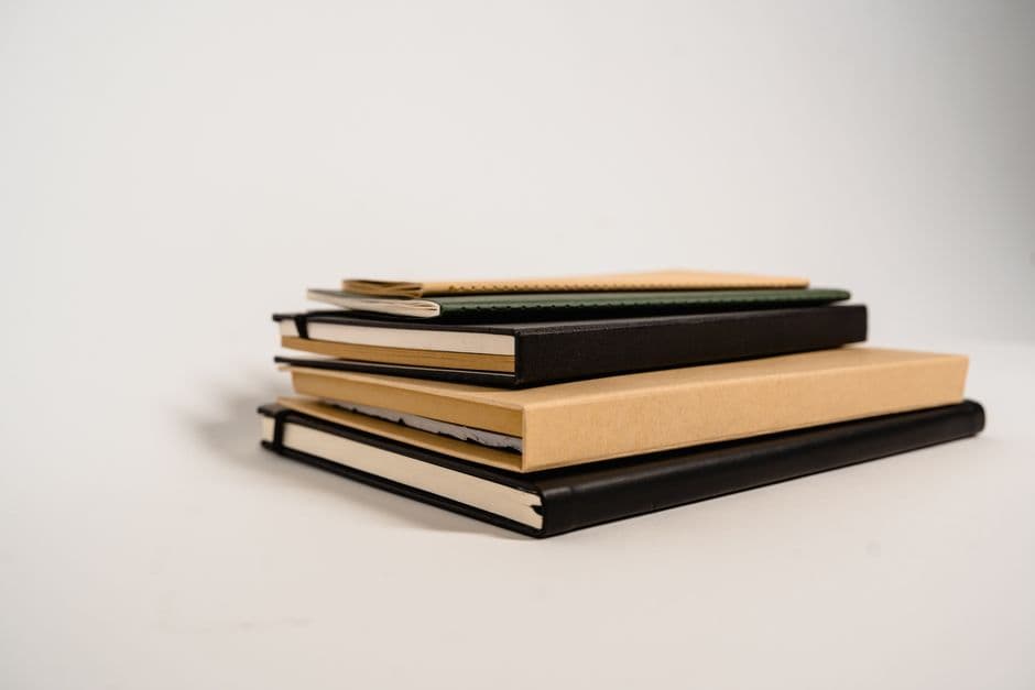 A stack of assorted notebooks in different colors and textures