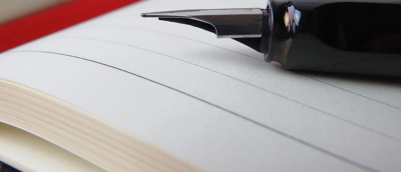 A fountain pen resting on an open lined notebook