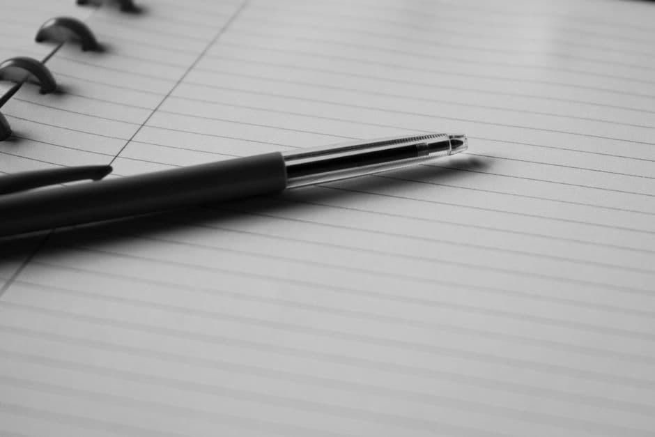A pen resting on an open lined notebook