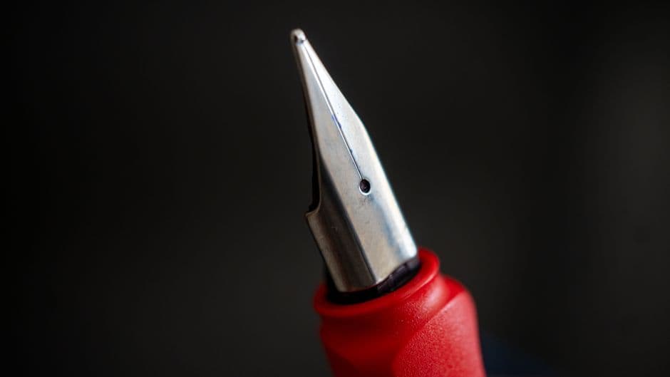 A close-up of a fountain pen nib against a dark background