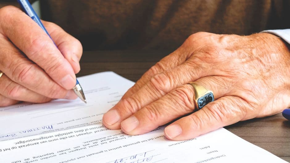 A person signing a document with a pen