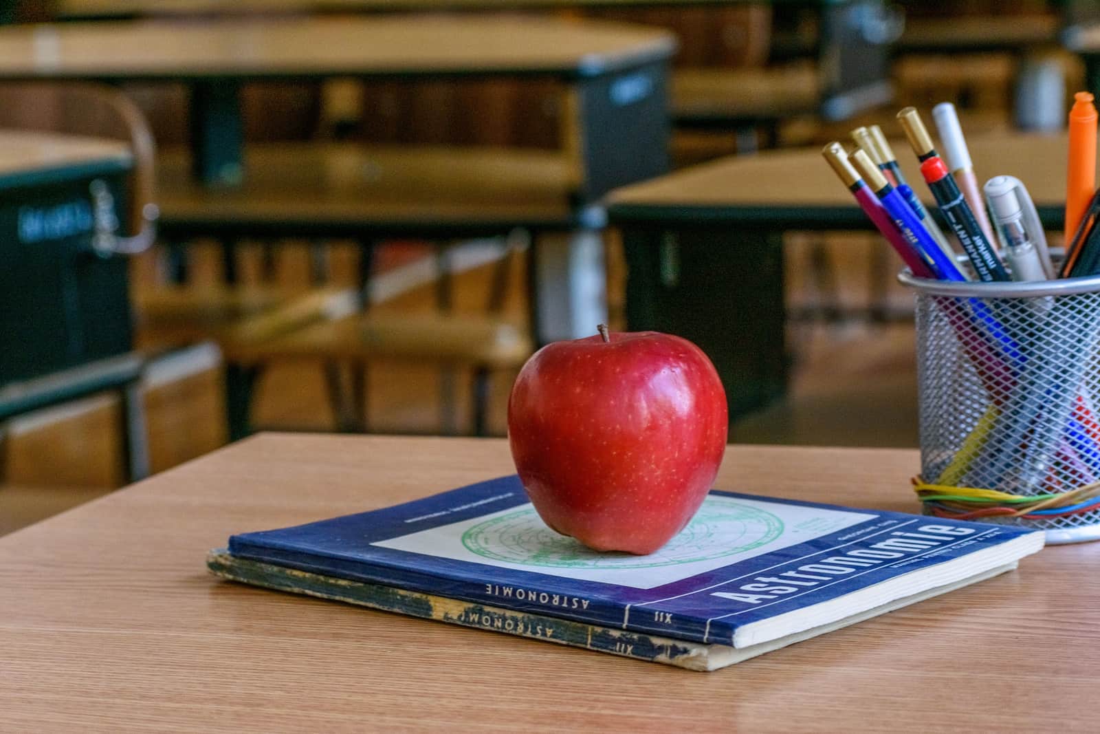 A pen resting on a marked exercise book on a teacher's desk