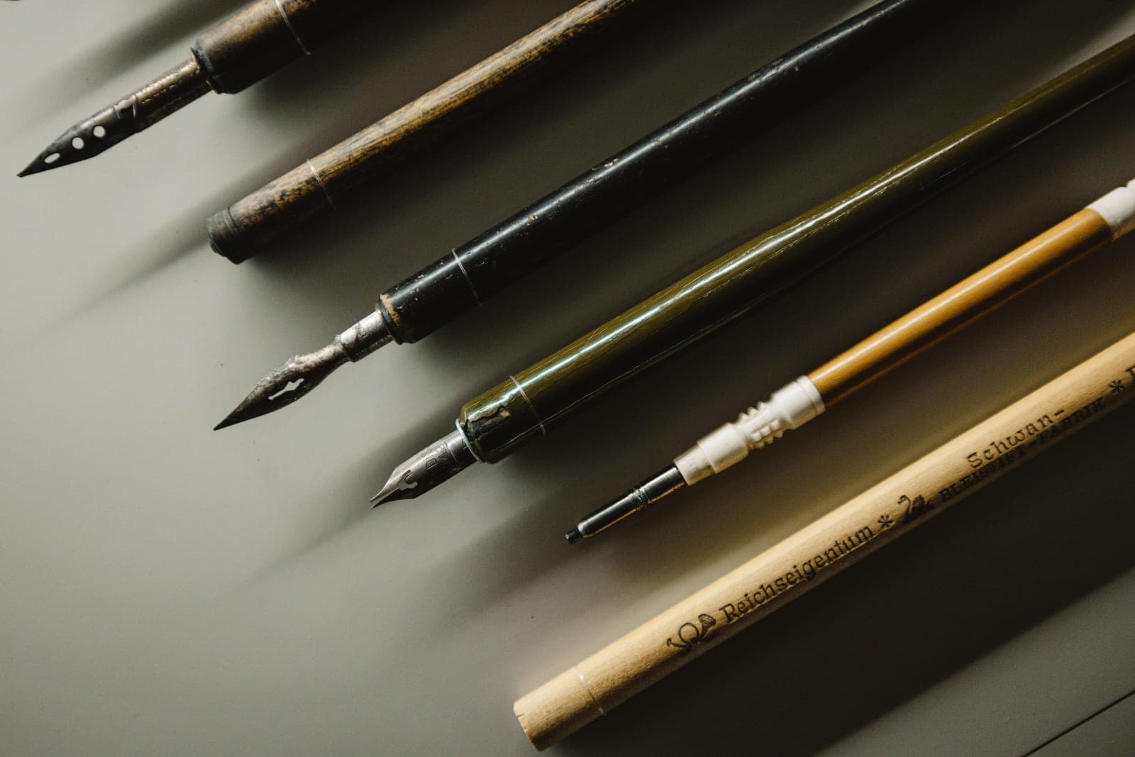 Fountain pens laid on a wooden desk in warm light