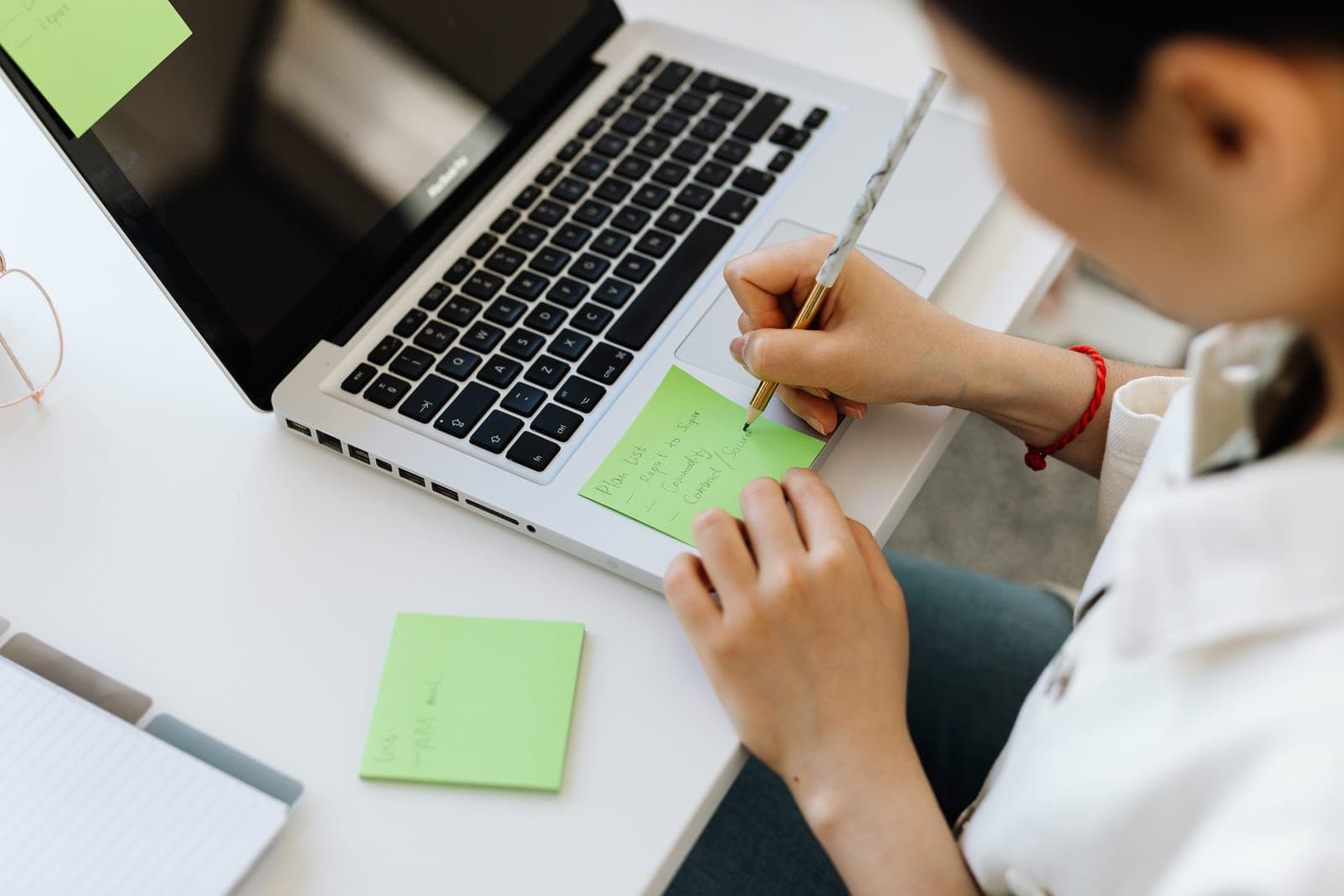 A person writing a to-do list in a planner at a desk