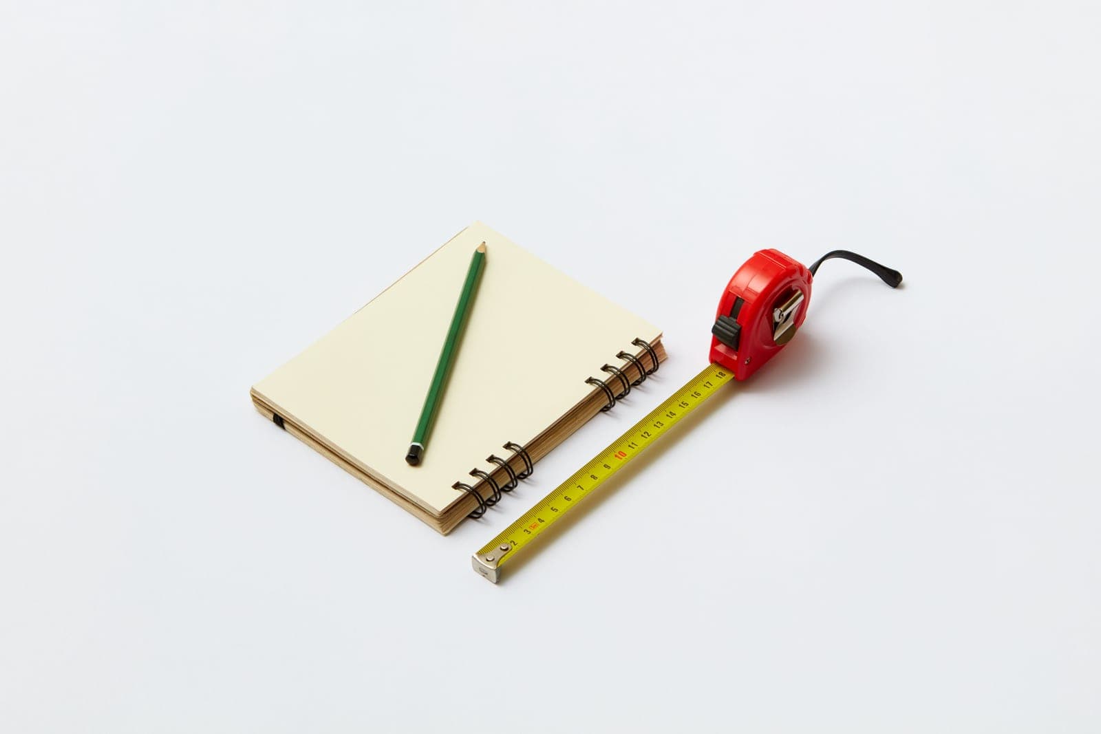 Notebooks of several sizes stacked beside a measuring tape