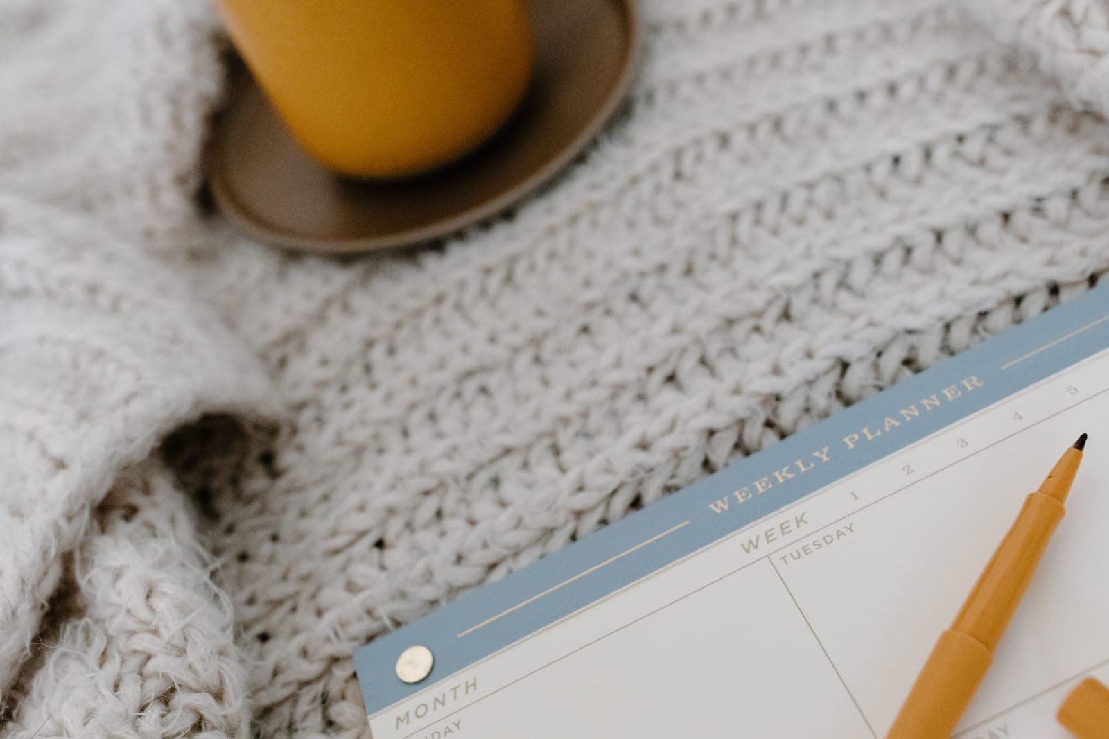 An open weekly paper planner with a pen and a cup of coffee